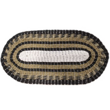 Oval-shaped woven seagrass mat with black, white, and beige pattern.